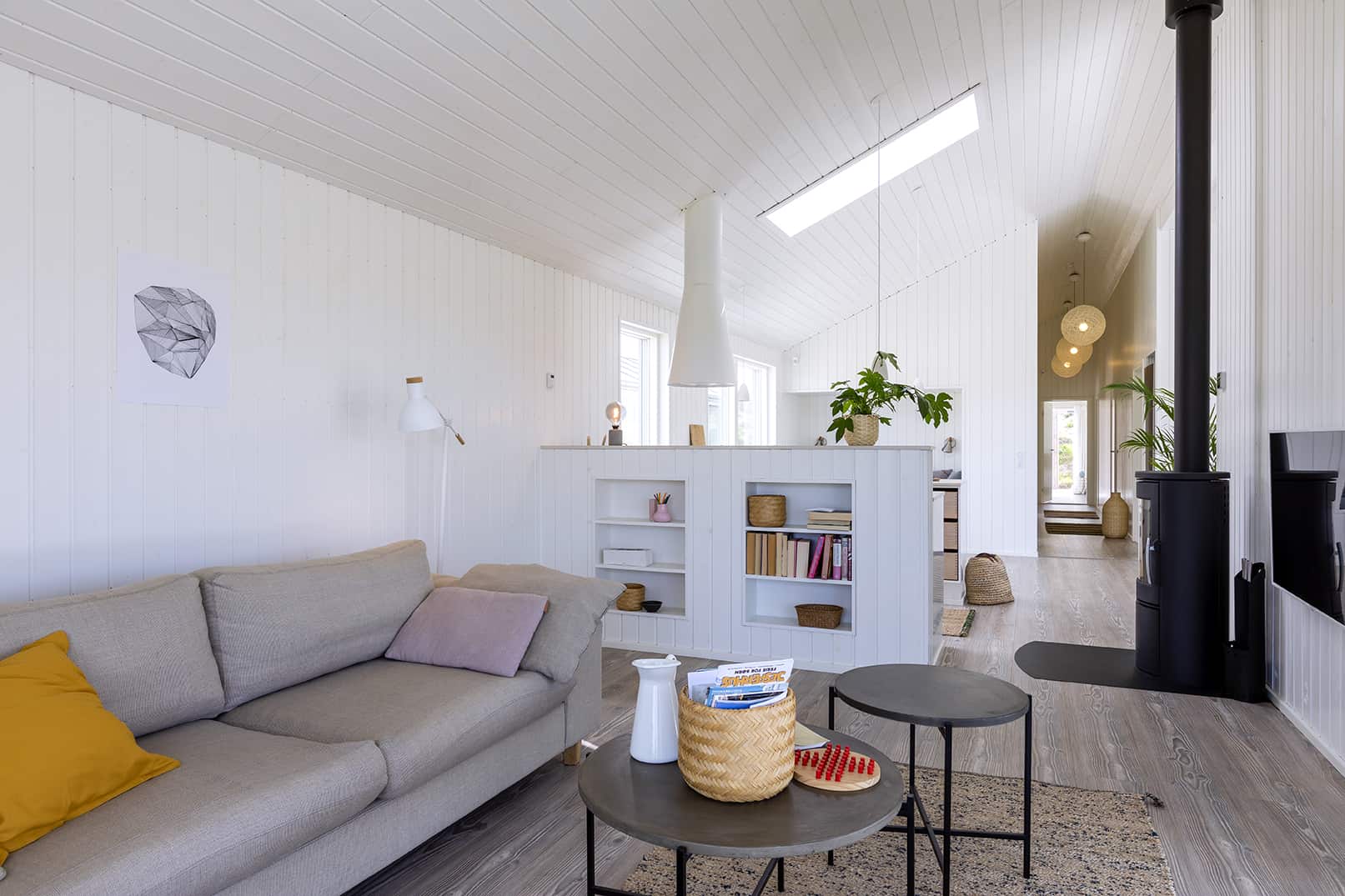 Sommerhusstue med sofa, ovenlysvindue, brændeovn