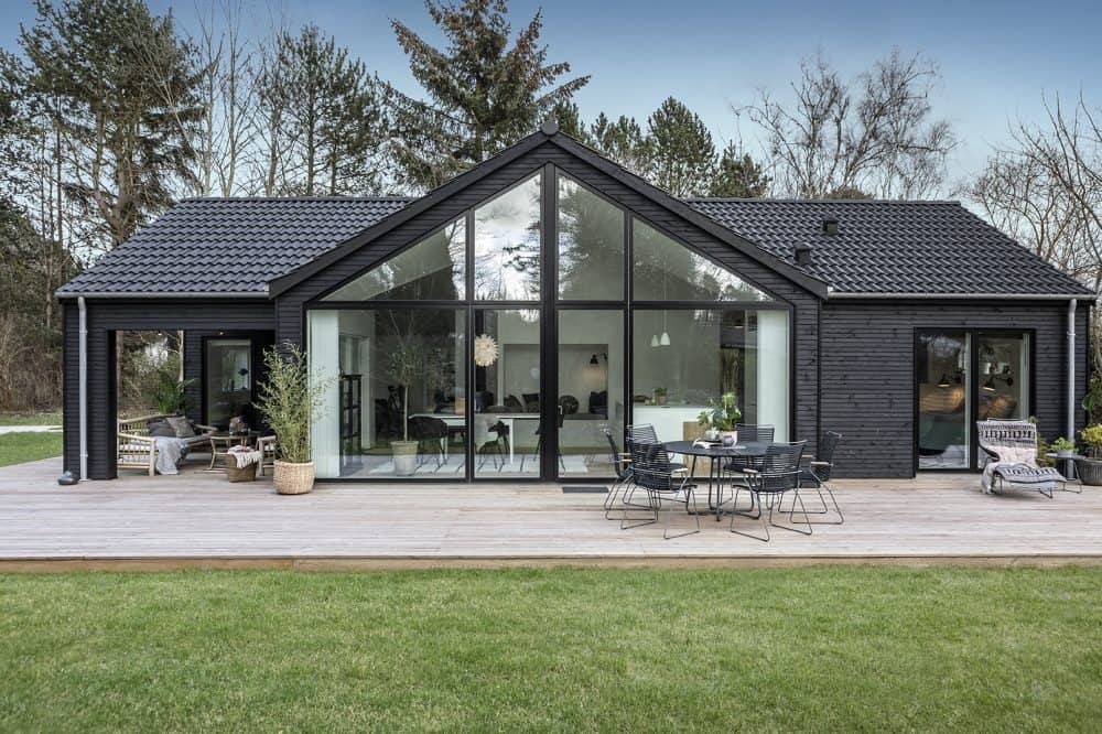 et sort skanlux sommerhus med træterasse
