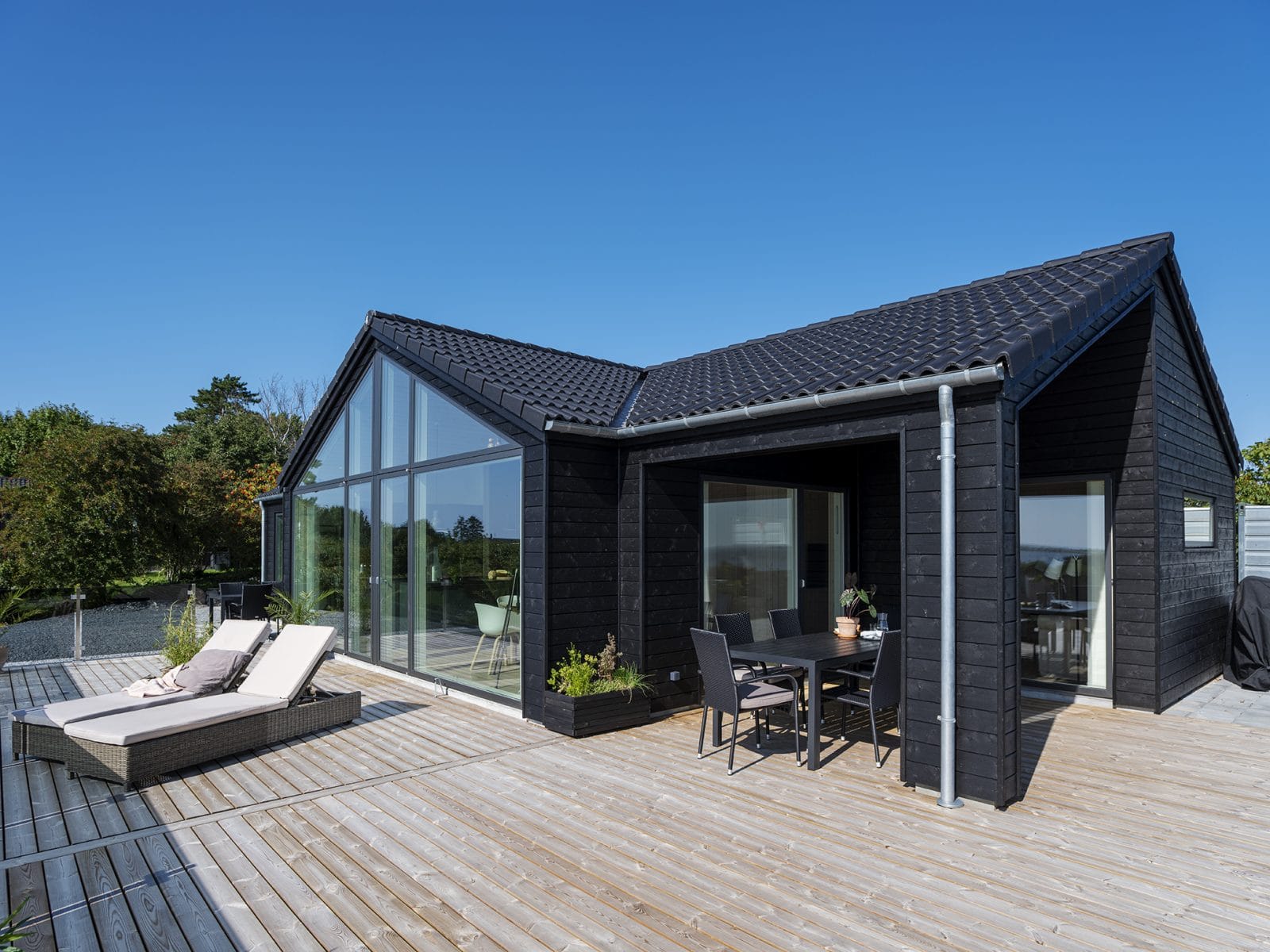 Sort sommerhus med stort vinduesparti set fra terrrasse
