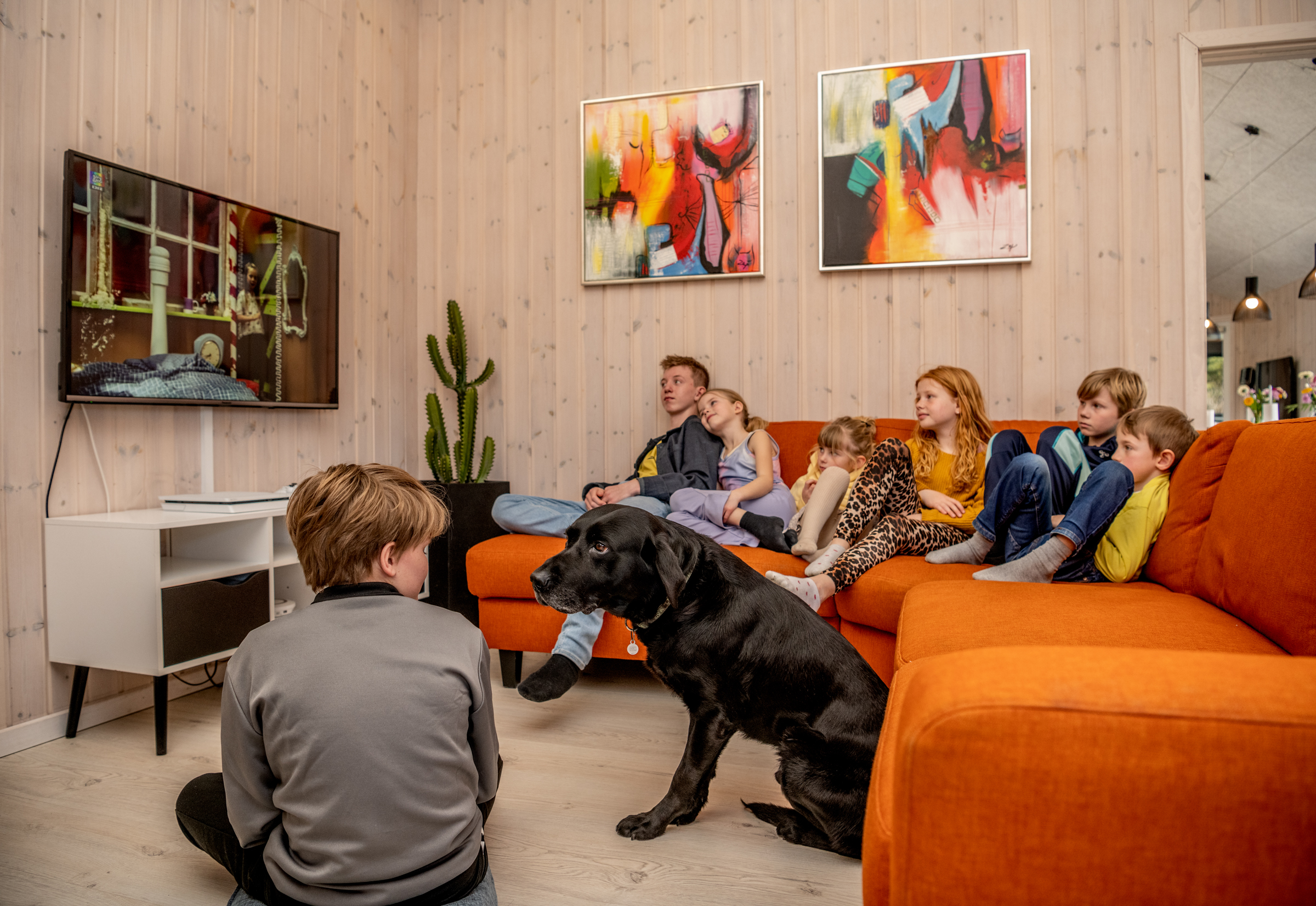 Familie ser tv fra orange sofa