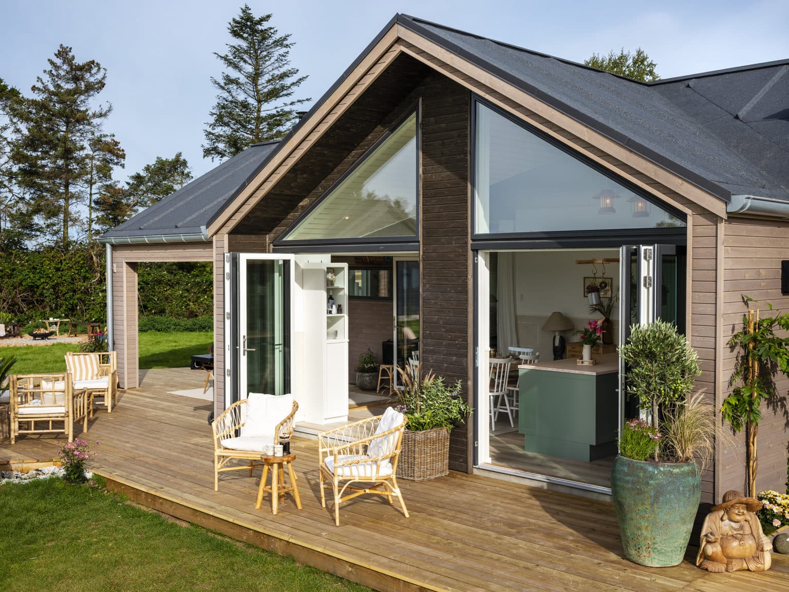 Stort vinduesparti i brunt sommerhus ud til terrasse