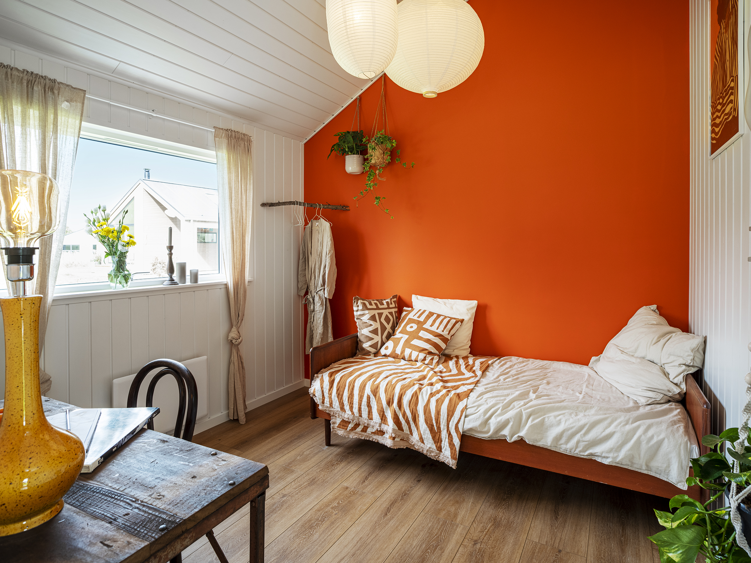 Værelse med en lille seng, skrivebord og rød væg